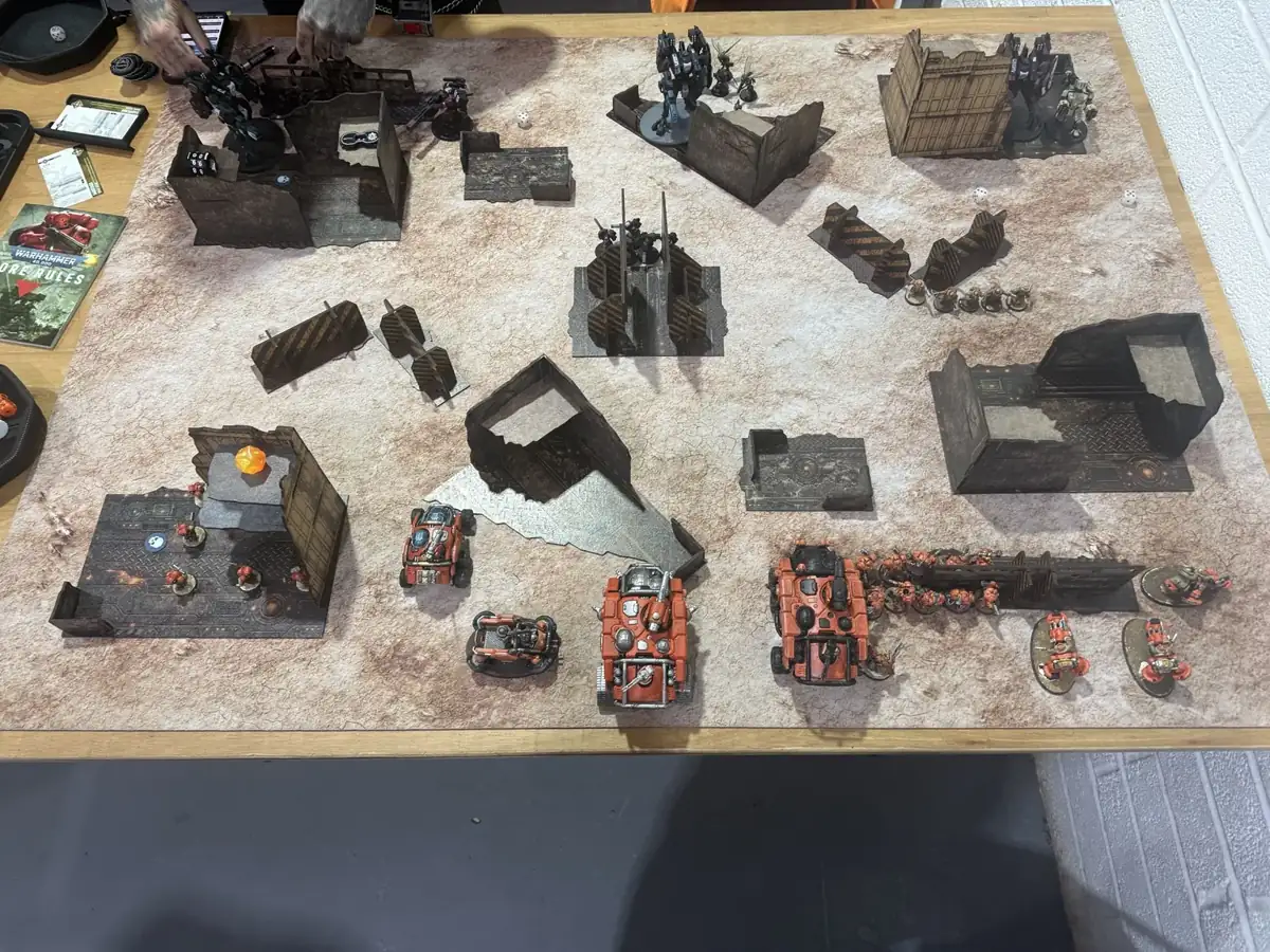 Overhead photograph of the game’s deployment, with orange Votann models in the foreground and T’au battlesuits across the table